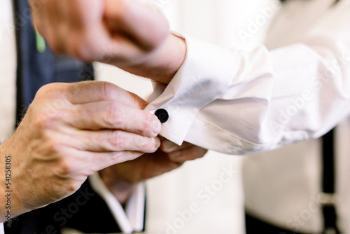 Man's hands helping another man with his cufflinks
