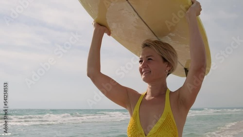 Woman surfer with surfboard goes along ocean beach.