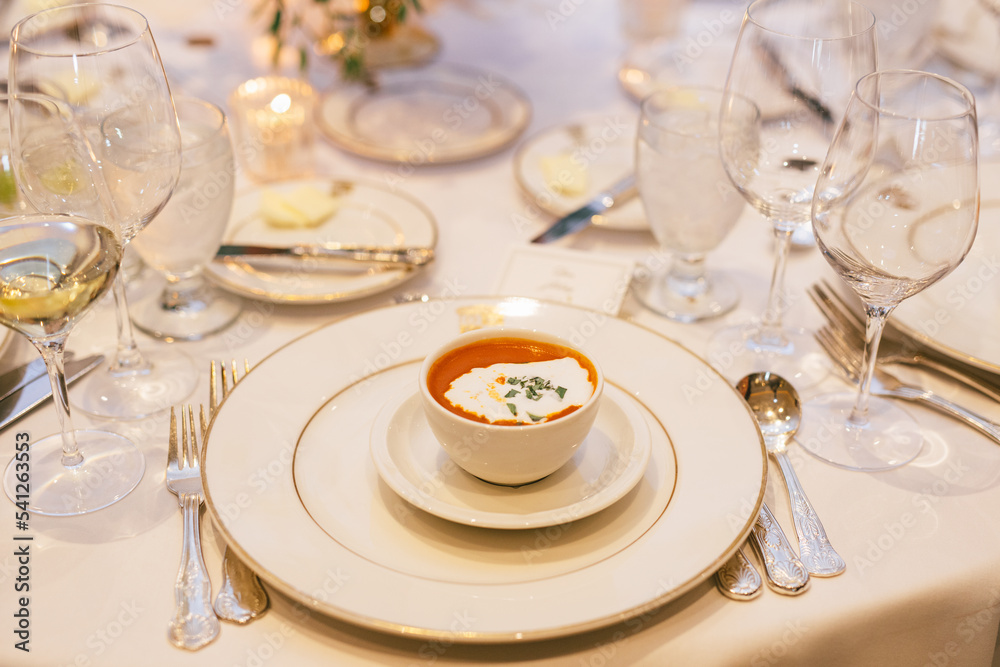 Tomato soup served on a fancy dinner restaurant with plates and silverware and glassware