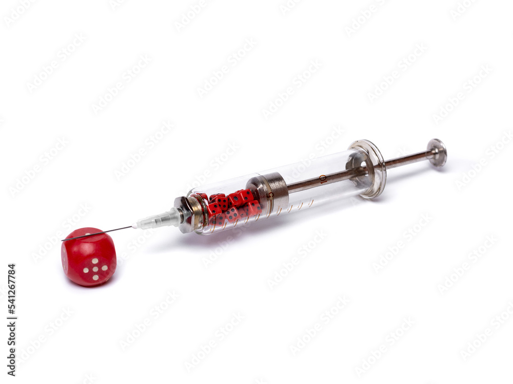 Composition of a glass syringe filled with small red gaming cubes, lying on a large red gaming cube. The problem of gambling addiction. Idea for halloween, decorations. Isolated on white background Composition of a glass syringe filled with small red gaming cubes, lying on a large red gaming cube. The problem of gambling addiction. Idea for halloween, decorations. Isolated on white background