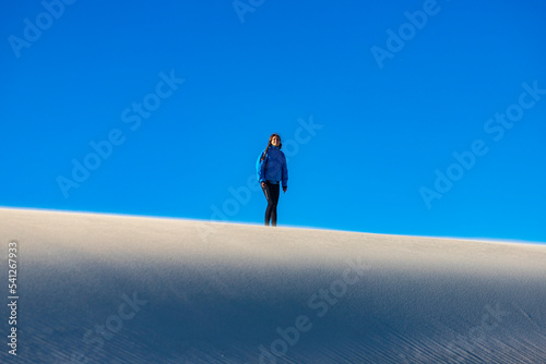 a girl walks along the top of a huge sand dune in coral bay western australia; walking in the sandy desert in the australian outback