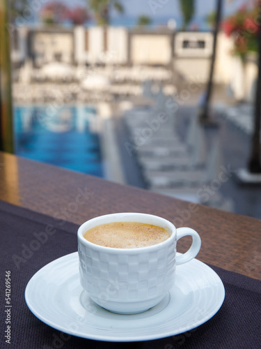 Delicious cup of coffee on table on balcony at the swimming pool in luxury hotel resort  vertical