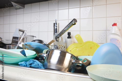 There is a lot of dirty dishes in the kitchen sink. Dirty dishes and unwashed kitchen appliances filled the kitchen sink.