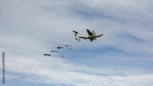 Royal Air Force Airbus A400M Atlas military cargo airplane (RAF ZM409) on a low level run drops several large containers by parachute