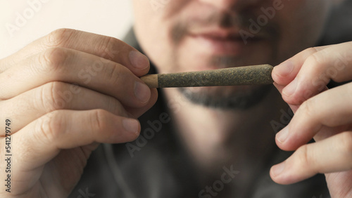 Young man holding marijuana joint in hands, CBD cannabis close up, © Ievgen Skrypko