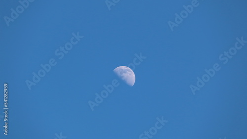 The moon shining in the daytime against the blue sky