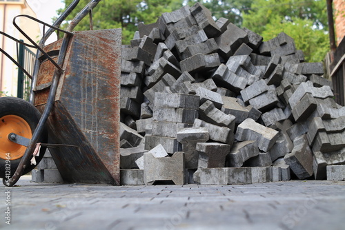 Paving stones stacked on top of each other. There is a wheelbarrow next to it.