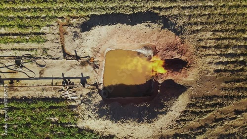 Hoses connected to gas equipment, pipes. Drone shooting of pit filled with water. Pattern. Green field. Amazing rural landscape. Outdoor. Summer, out of town. Daytime, countryside