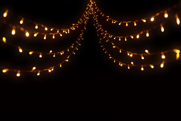 Abstract Christmas lights on black background. Glowing light bulb garland,
