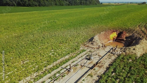 Close-up footage of gas installation. Fire burning in pit. Metal supports, concrete foundation outdoors near enterprise. Pumps and equipment. Out of town. Summer, daytime, sunny day. Work