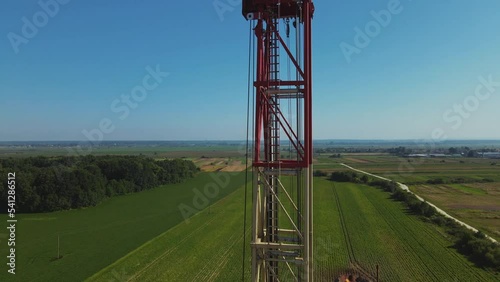 Drone shot of gas tower with flag of Ukraine. Beautiful natural rural landscape. Green forest on background in summertime. Outdoor. Horizontal footage