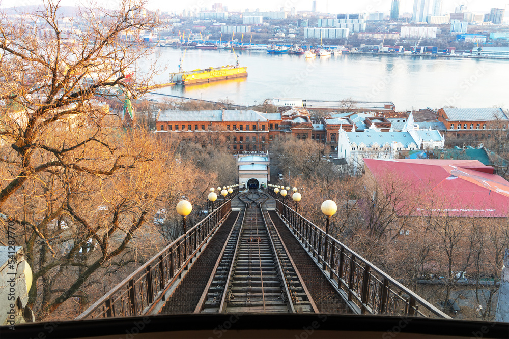 Fototapeta premium View of funicular rails, Golden Horn Bay and city of Vladivostok, Russia from cab of funicular on slope of Eagle Hill. Rail transport