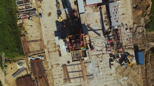 Flag of Ukraine on tower of enterprise. Pipes of different types. Сoncrete pad. Settlement. Aerial view. Drone footage. Pumps and equipment. Summer, daytime, sunny day. Work, job concept. Gas