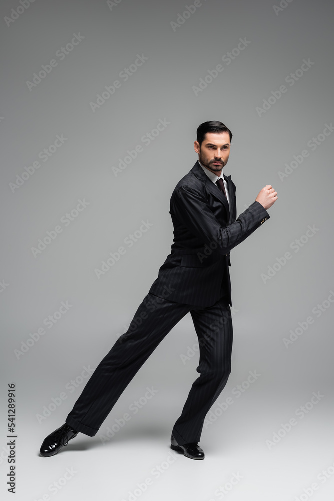 Professional dancer in suit performing tango on grey background Professional dancer in suit performing tango on grey background