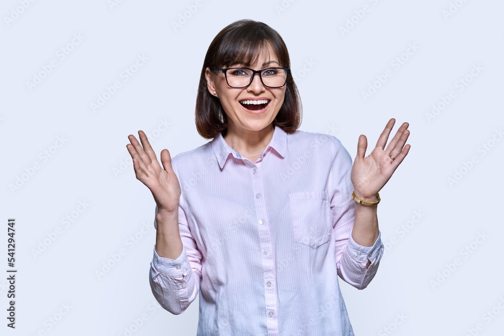 Happy emotional middle aged woman looking at camera on light background Happy emotional middle aged woman looking at camera on light background