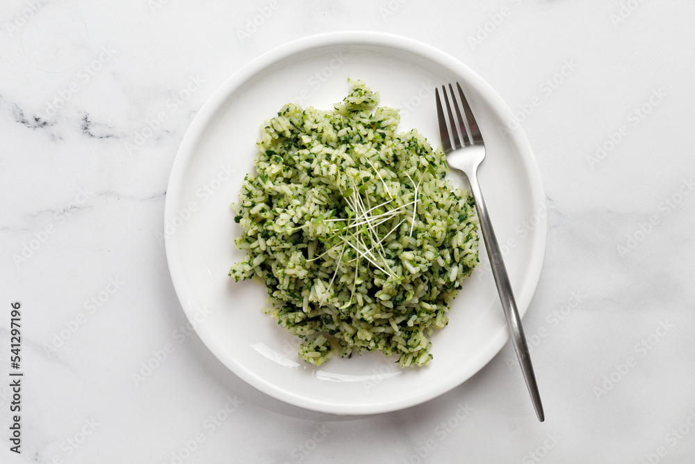 Green Rice with Spinach. Spinach Rice with microgreens on white plate with fork on marble Background, Healthy Vegetarian diet Food. Green Rice with Spinach. Spinach Rice with microgreens on white plate with fork on marble Background, Healthy Vegetarian diet Food.