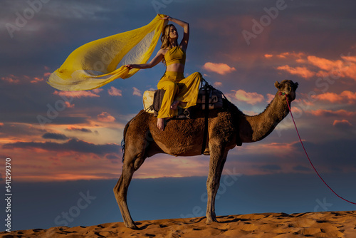 A Lovely Model Rides A Dromedary Camel Through The Saharan Desert On Their Camels In Morocco photo