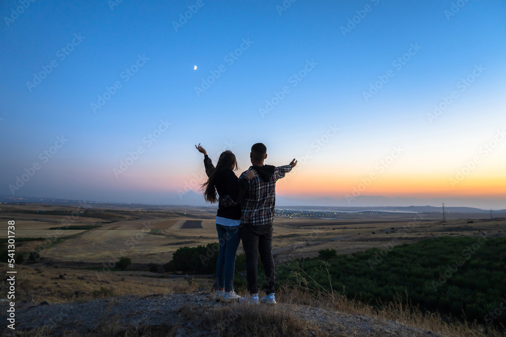 Couple with raised hands at sunset