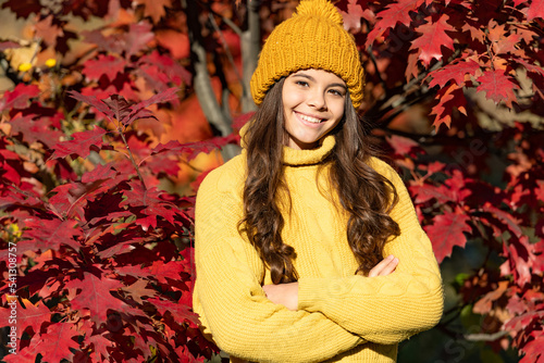 Child girl on autumn fall background, autumn kids face. cheerful teen kid in hat at autumn leaves on natural background