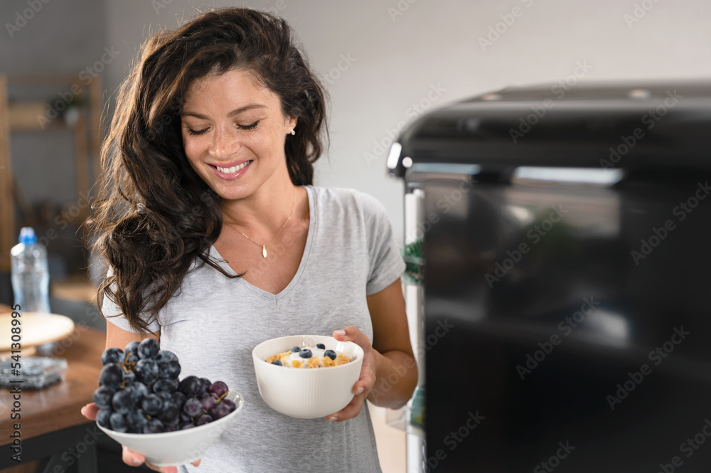 Beautiful young smiling pregnant woman taking healthy food from a