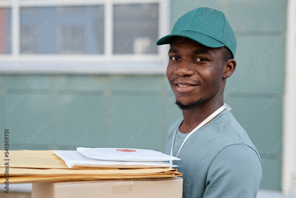 Portrait of African American delivery worker holding box and smiling at camera Portrait of African American delivery worker holding box and smiling at camera