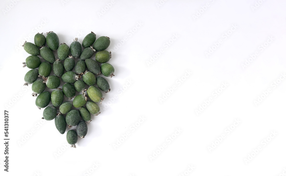 Feijoa fruits on a white background, laid out in the form of a heart. There is a place for the text. Feijoa fruits on a white background, laid out in the form of a heart. There is a place for the text.