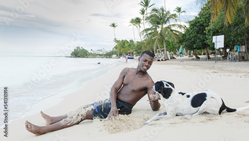 Black man caressing dog on beach