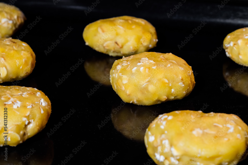 Close up view: many uncooked homemade oatmeal cookies on metal sheet in oven, black background. Dessert, cookery, baking, gastronomy and raw concept Close up view: many uncooked homemade oatmeal cookies on metal sheet in oven, black background. Dessert, cookery, baking, gastronomy and raw concept