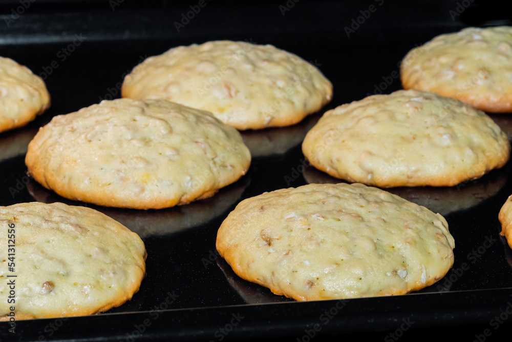 Close up view: process of cooking many homemade crunchy oatmeal cookies on metal sheet in oven. Dessert, cookery, baking, gastronomy concept