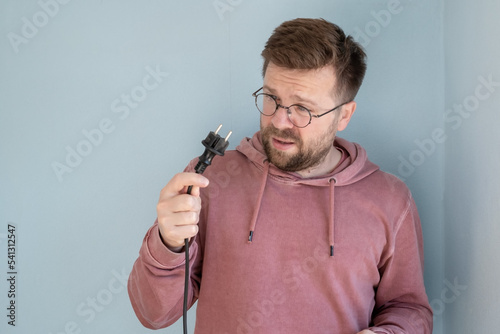 Εκτύπωση καμβά Man with bewilderment looks at a faulty electric plug with a cord
