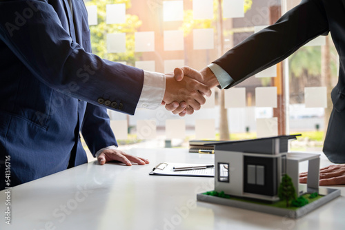 Shake hand Real estate brokerage agent Deliver a sample of a model house to the customer, mortgage loan agreement Making lease and buy and sell house And contract home insurance mortgage loan concept