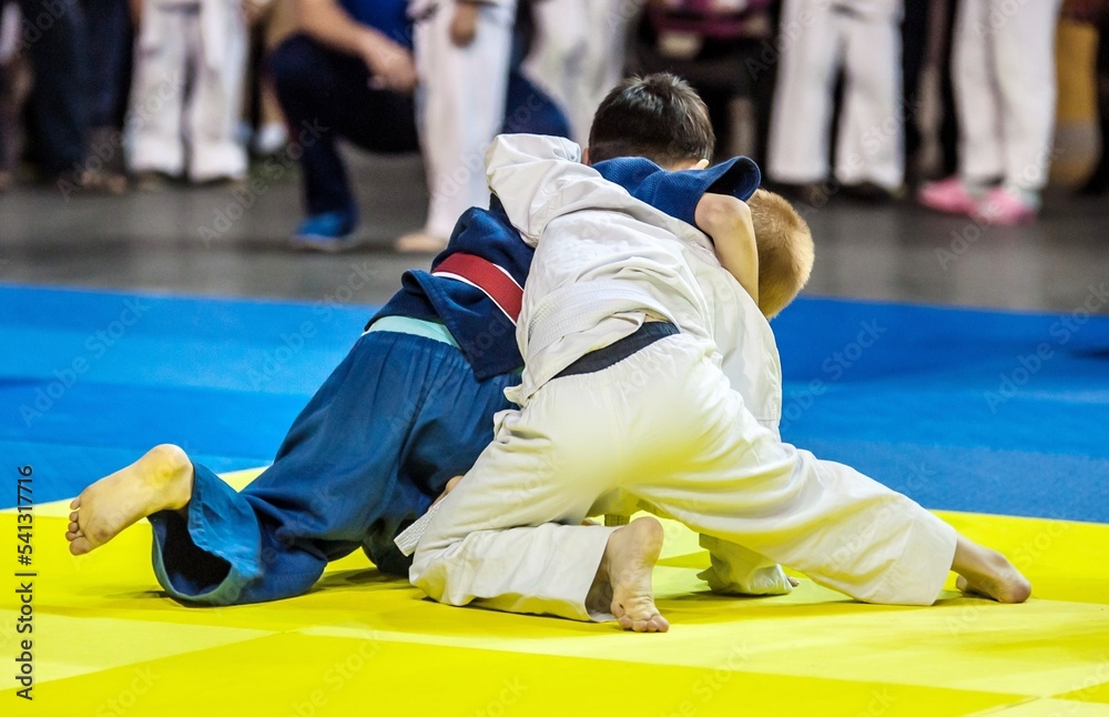 Two boys fighter judoka in judogi compete on the tatami Two boys fighter judoka in judogi compete on the tatami