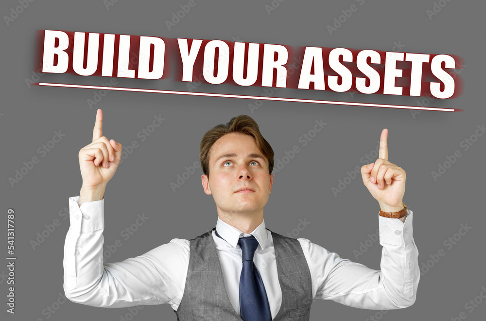 Businessman points fingers at the inscription - Build Your Assets Businessman points fingers at the inscription - Build Your Assets