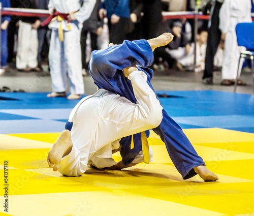 Two boys fighter judoka in judogi compete on the tatami 