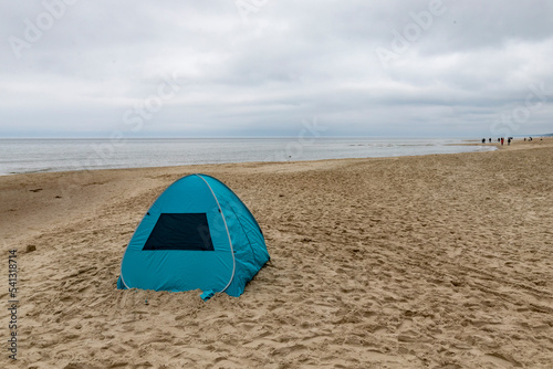 A lonely tent on an empty sea beach. The scenery is slightly hazy.