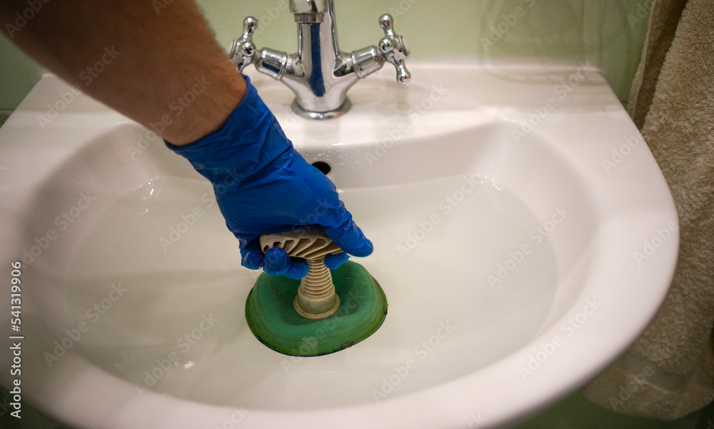 A hand with a plunger of green color.Break through the water blockage