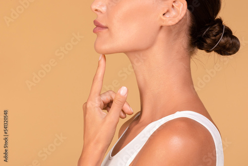 Chin augmentation. Side view of unrecognizable young woman touching her face, happy with result of plastic surgery photo