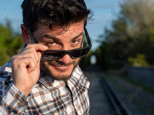 Hombre apuesto mirando a cámara con expresión de complicidad photo
