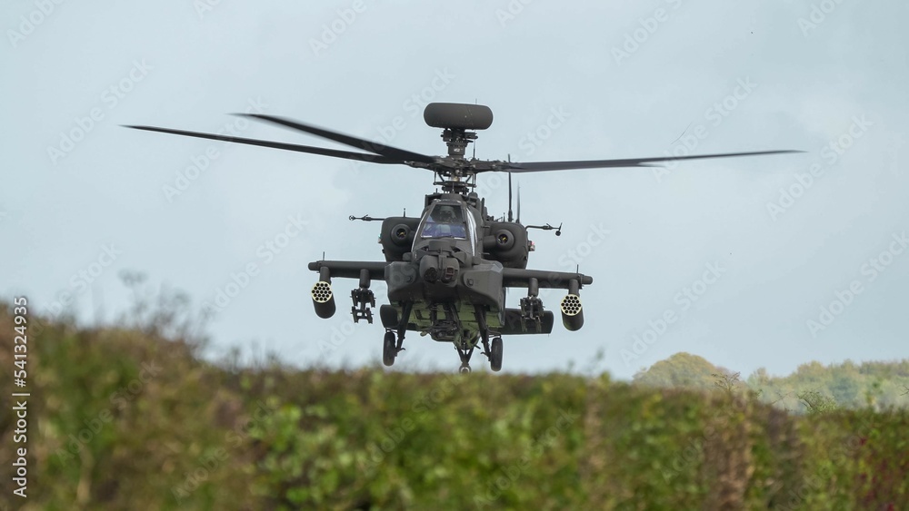 close-up head on view of ZM707 British army Boeing Apache Attack helicopter gunship (AH64E AH-64E ArmyAir606) hovering low behind hedgerow close-up head on view of ZM707 British army Boeing Apache Attack helicopter gunship (AH64E AH-64E ArmyAir606) hovering low behind hedgerow