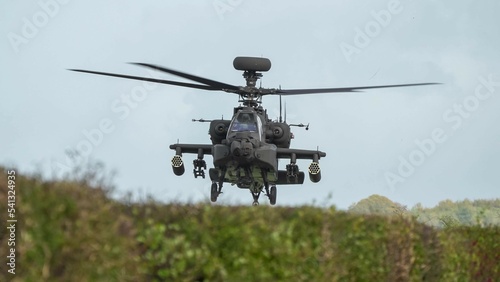 Fototapeta Naklejka Na Ścianę i Meble -  close-up head on view of ZM707 British army Boeing Apache Attack helicopter gunship (AH64E AH-64E ArmyAir606) hovering low behind hedgerow