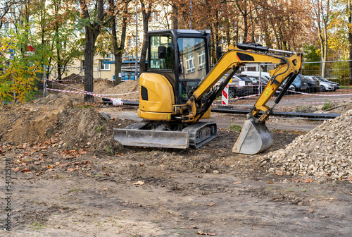 Small bulldozer at work. Orange excavator on the road. Construction works in the city. 