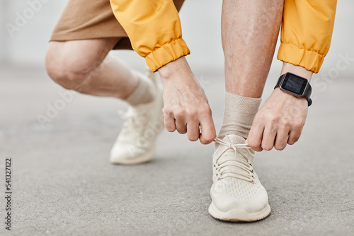 Minimal closeup of unrecognizable man tying shoe laces during outdoor run, copy space © Seventyfour