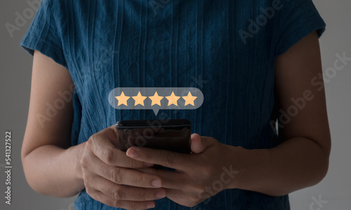 close up Woman hand using smartphone with popup five star icon for feedback review satisfaction service, Customer service experience and business satisfaction survey.