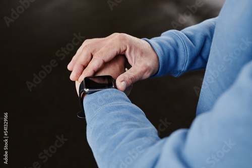 Close up of unrecognizable man setting up smartwatch against black background, copy space