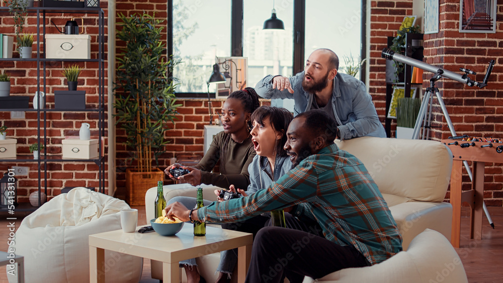 Diverse people playing video games online on console, using controller to have fun at gathering with beer bottles. Friends enjoying gaming competition on television, entertainment group. Diverse people playing video games online on console, using controller to have fun at gathering with beer bottles. Friends enjoying gaming competition on television, entertainment group.