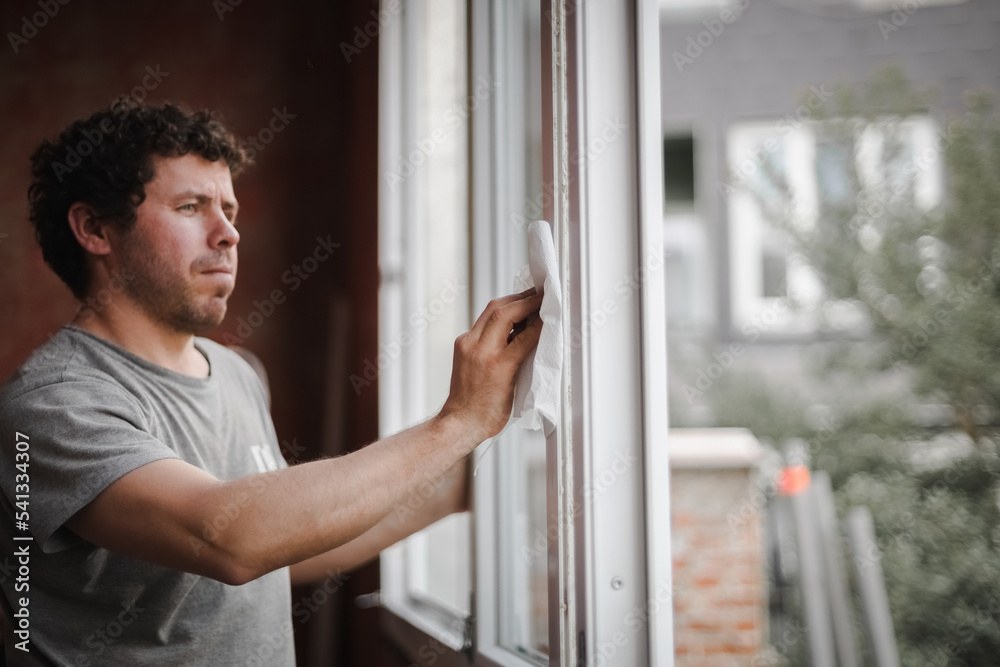 Caucasian man cleans the window frame. Caucasian man cleans the window frame.