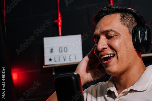 Host Talking and smiling on mic in a stream, podcast show, with headset (headphones) red and black background photo