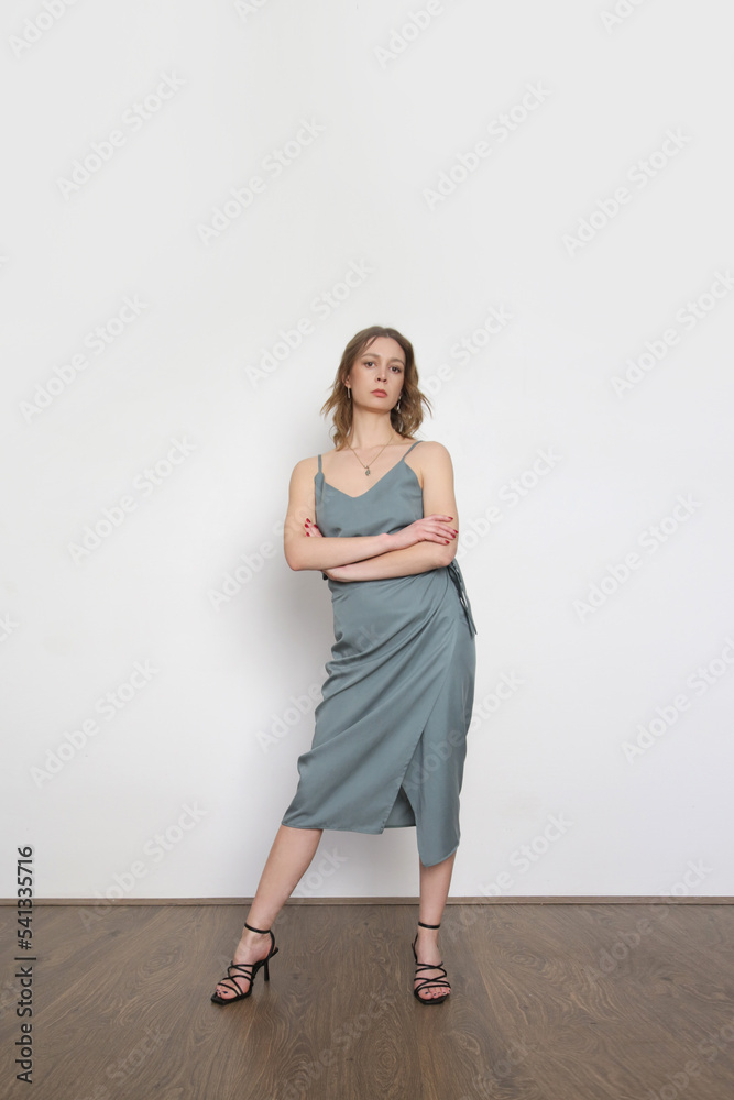 Female model wearing bluish grey camisole silk top and wrapped midi skirt. Stylish monochrome summer outfit. Fashion Studio shot. Female model wearing bluish grey camisole silk top and wrapped midi skirt. Stylish monochrome summer outfit. Fashion Studio shot.