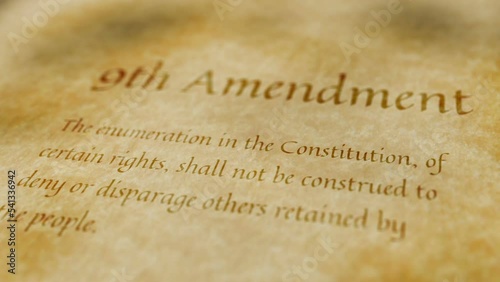 Scrolling text on old paper background of contents of 9th amendment to the United States Constitution that guarantees that people have rights other than those explicitly guaranteed in Bill of Rights