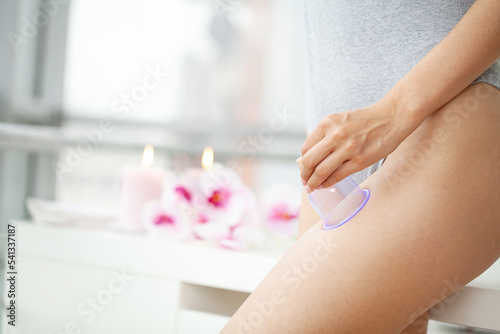 Woman getting anti-cellulite massage of leg with use of vacuum cans